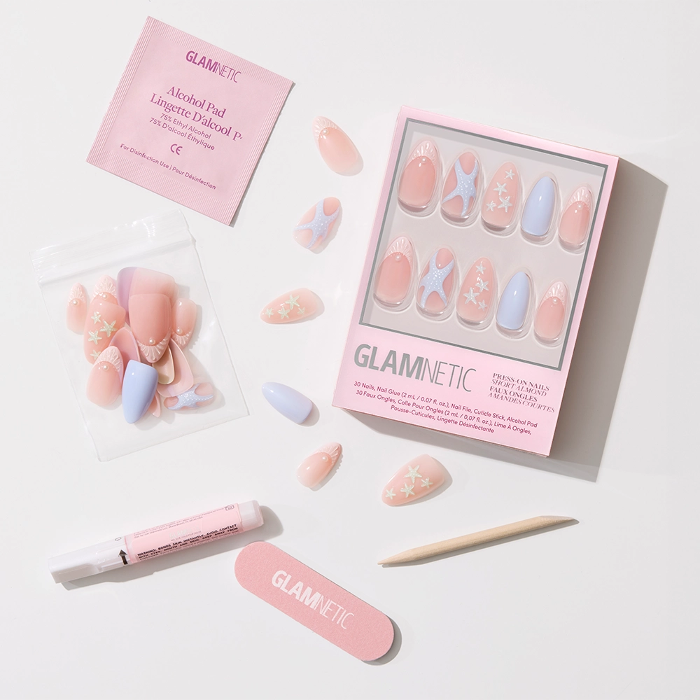 Introducing the glamnetic Salty Waves Press-On Nail Set—short almond nails in pink and pastel blue with floral designs. Includes a pink nail file, cuticle stick, nail glue, alcohol pad, and extra nails, all displayed on a white background. - Product image