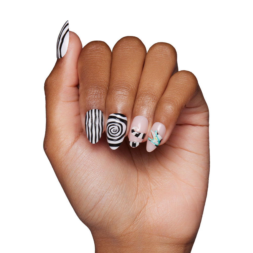 A hand with medium brown skin displays nails featuring black and white abstract stripes, spirals, and geometric patterns from the glamnetic Sandworm set, accented by teal, gold, and bold 3D designs against a white background. - Product image