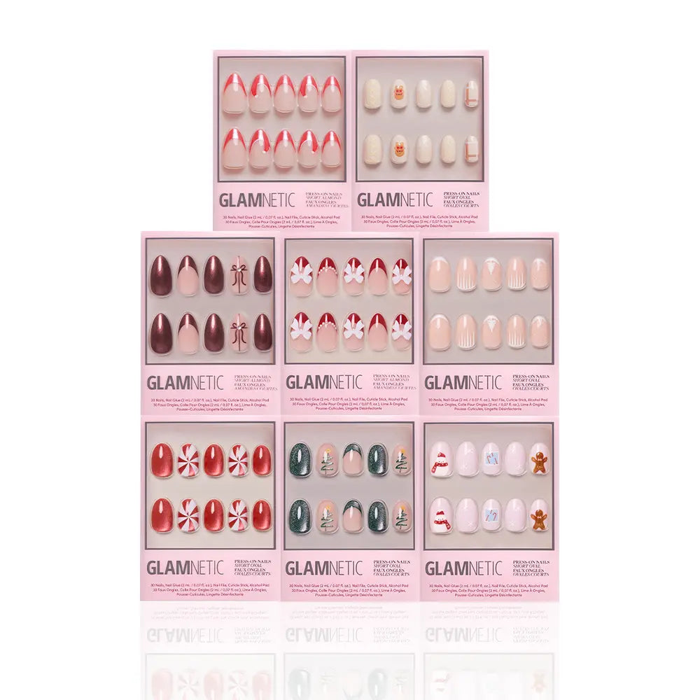 Eight boxes of glamnetic's Santa's Workshop festive press-on nails, featuring designs like candy canes, peppermints, snowflakes, gingerbread men, and bright Christmas colors, are displayed against a white background. - Product image