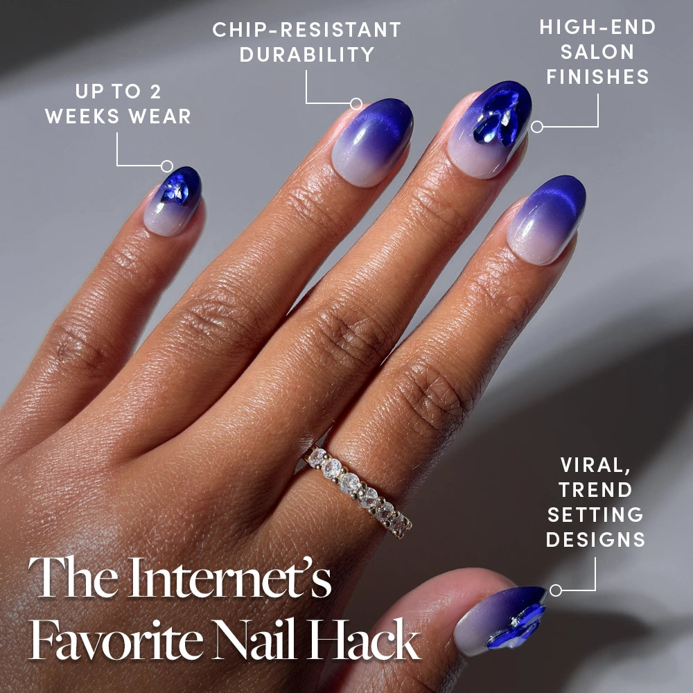A hand adorned with glamnetic Sapphire Press-On Nails—in a striking blue and purple gradient with jeweled accents and a gold ring—captures the allure of these elegant, jewel-encrusted nails. Text highlights long wear, chip-resistant durability, salon-quality finish, and on-trend designs for show-stopping style. - Product image