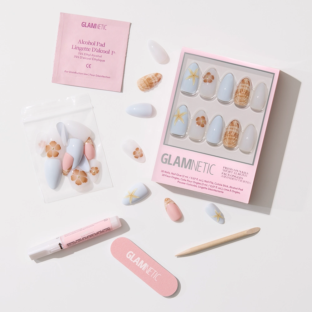 The glamnetic Sea Star Press-On Nail Set includes pastel nails with 3D shell and starfish accents, plus a nail file, cuticle stick, pink glue tube, alcohol pad, and extra nails arranged on a white background. - Product image