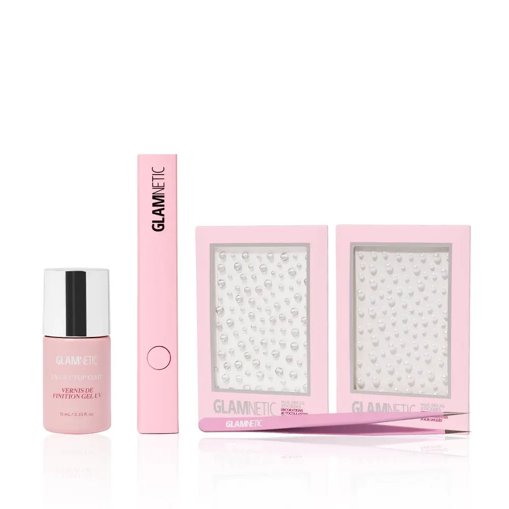 The glamnetic Seal The Spotlight set features a pink UV Gel Top Coat, a pink applicator tool, two trays of 3D mani nail gems, and a pink tweezer, all neatly arranged against a white backdrop. - Product image
