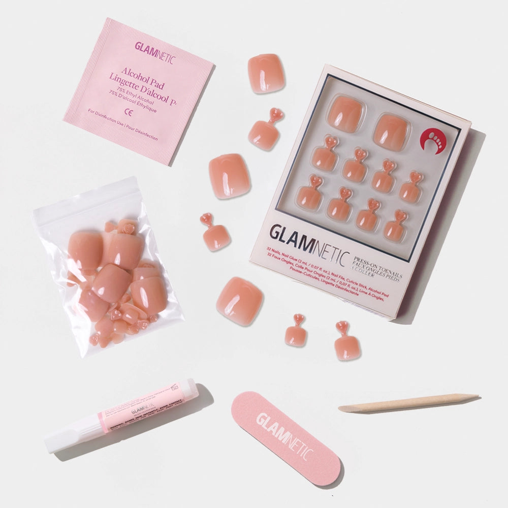 A flat-lay of the Glamnetic peach press-on toenail kit, including nails, glue, nail file, cuticle stick, and alcohol pad. - Product image