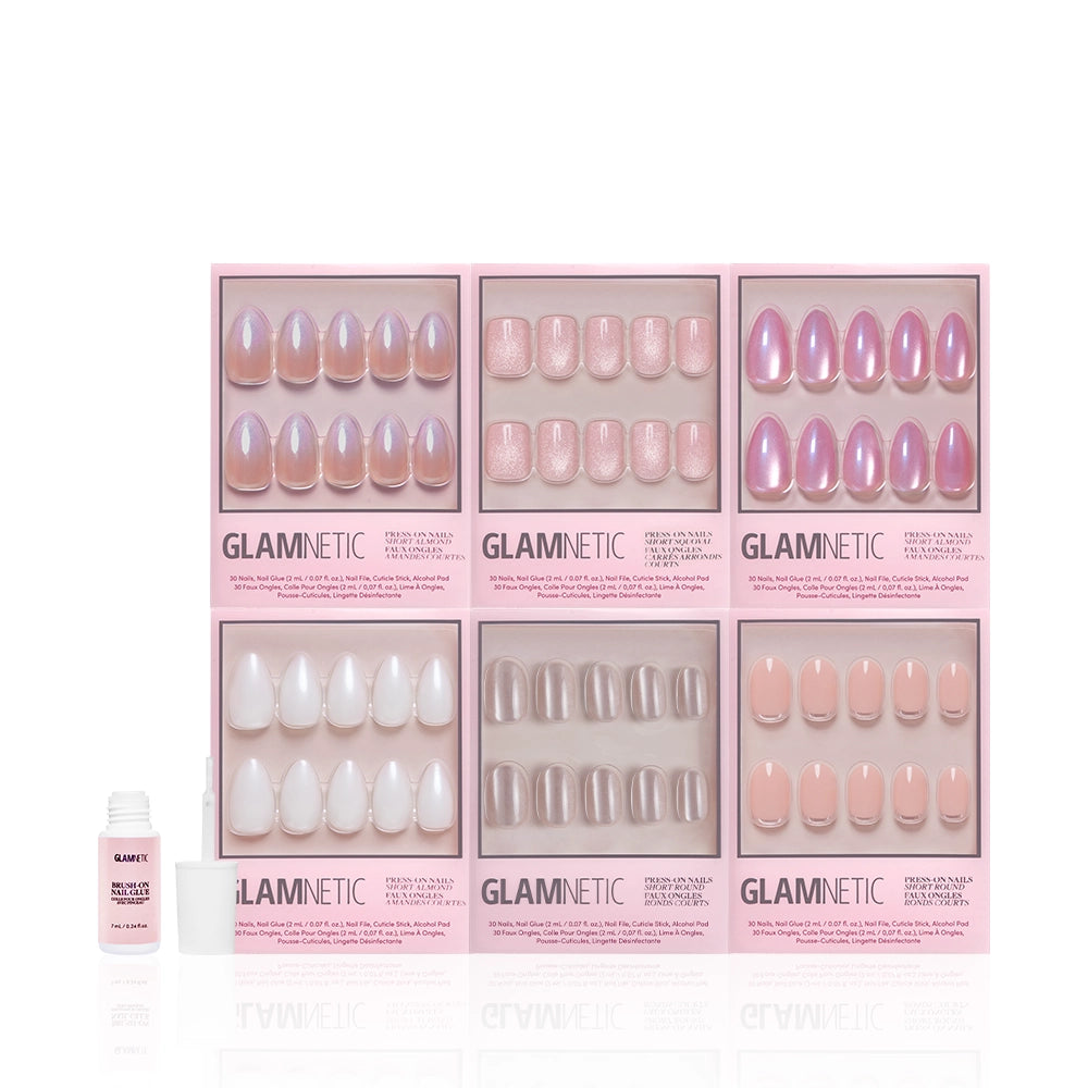 Six boxes of the glamnetic Shimmer Soiree Bundle press-on nails, showcasing nude and pink styles and velvet finishes, are arranged in two rows with a small bottle of nail glue placed below them on the left. - Product image