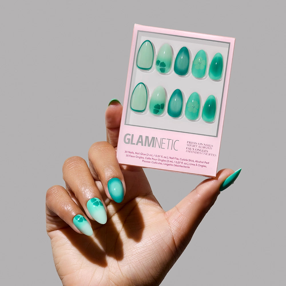 A hand with an aquamarine gradient and abstract leaf designs holds a box of glamnetic’s Siren Green Press-On Nails—just right for mermaid-inspired glam. - Product image