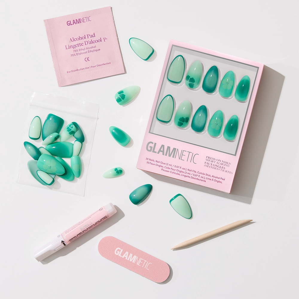 The glamnetic Siren Green Press-On Nails set includes aquamarine gradient nails, an alcohol pad, small file, wooden cuticle stick, nail glue, and extra nails—all neatly arranged in a pink Glamnetic box for mermaid-inspired style. - Product image