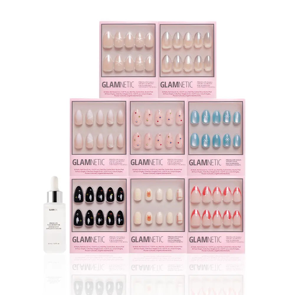 Eight boxes of glamnetic’s Snow Place Like Home Collection festive press-on nails, in assorted colors and designs, are stacked in two rows with a nail glue bottle placed in front, all set against a white background. - Product image