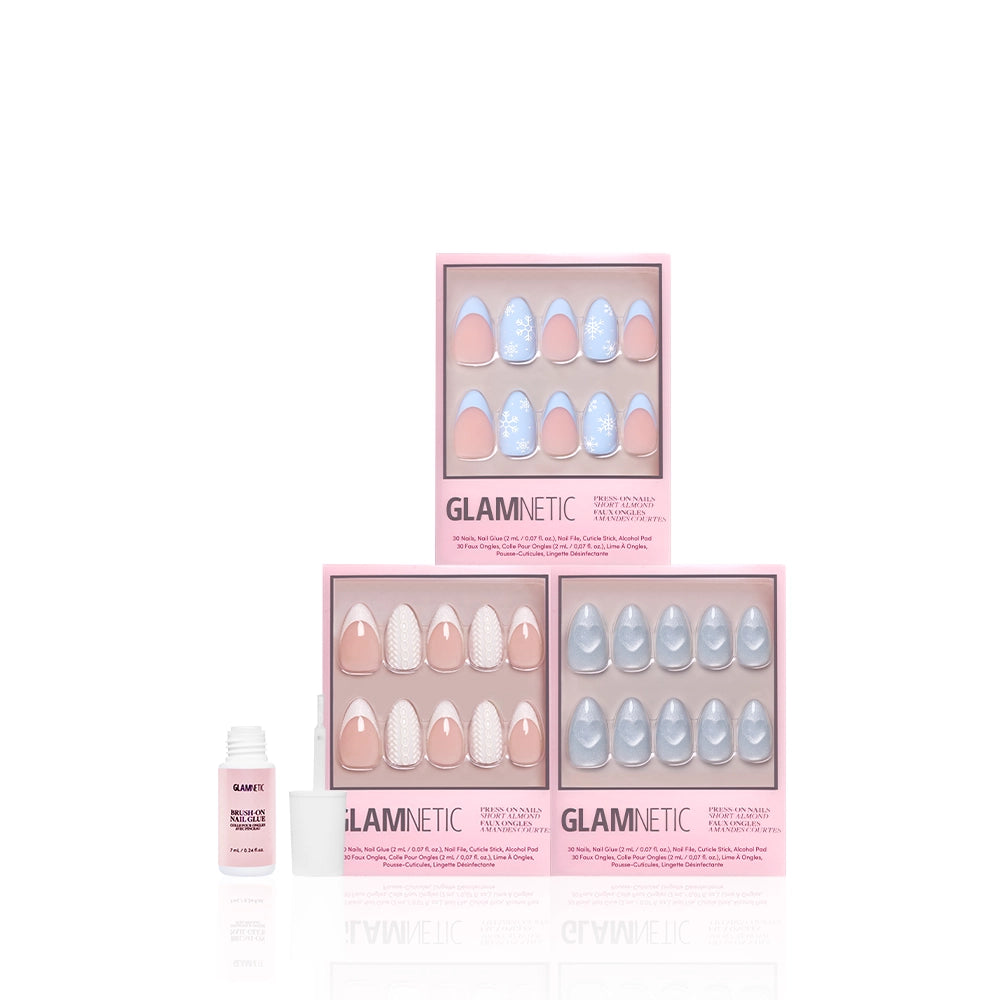 Three boxes of glamnetic Snow Play press-on nails with pink and blue short almond designs and glitter French tips are shown alongside a small bottle of nail glue on a white background. - Product image