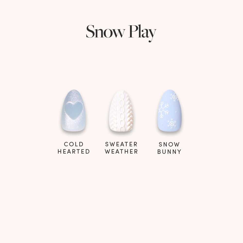 Glamnetic’s Snow Play set features three short almond nail designs: silver glitter French tips with a heart (Cold Hearted), white knit sweater with 3D detail (Sweater Weather), and light blue with white snowflakes (Snow Bunny).