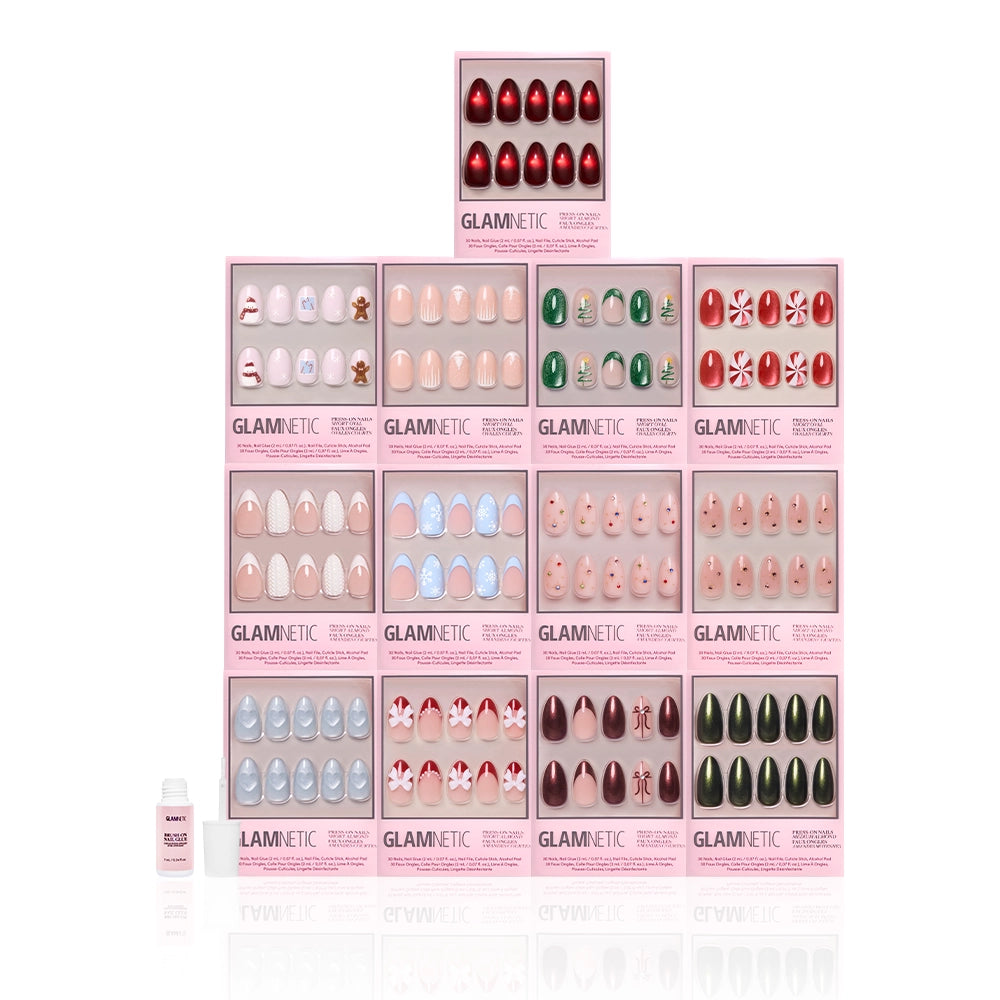 The glamnetic Snowed In Collection festive nail sets, featuring holiday designs, are stacked in a pyramid, with a small nail glue bottle in front left, all set against a white background. - Product image