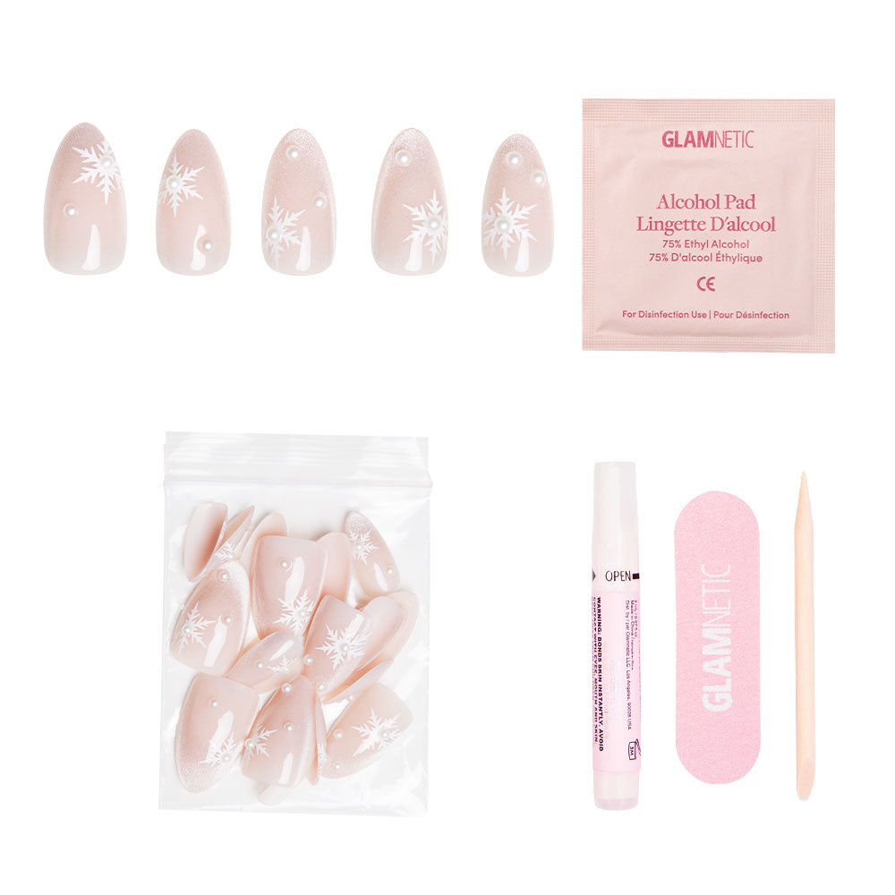 The glamnetic Snowfall set features short pink almond nails with snowflake designs, an alcohol pad, pink nail file, wooden cuticle stick, nail glue, and resealable bag with extra nails. - Product image