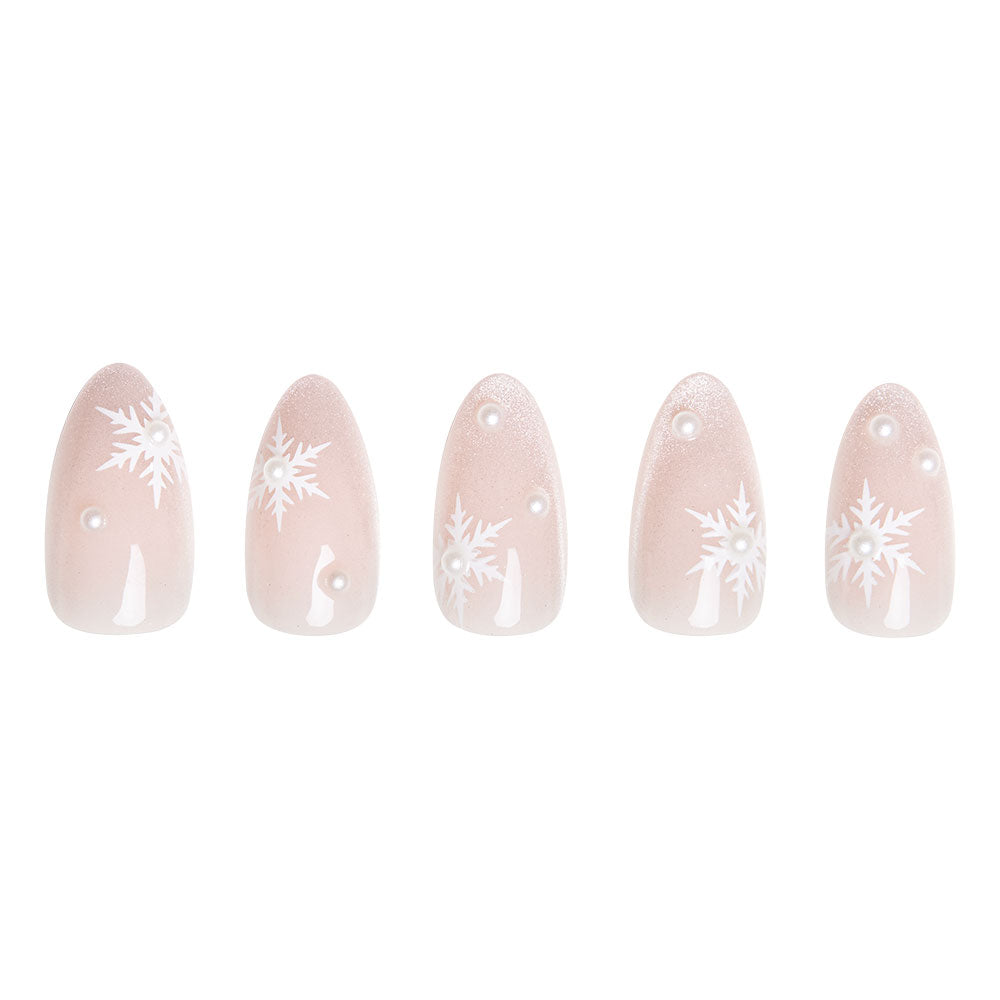 The Snowfall by glamnetic features five short almond nails with a light pink base, decorated with snowflakes and white dots, displayed in a row on a white background. - Product image