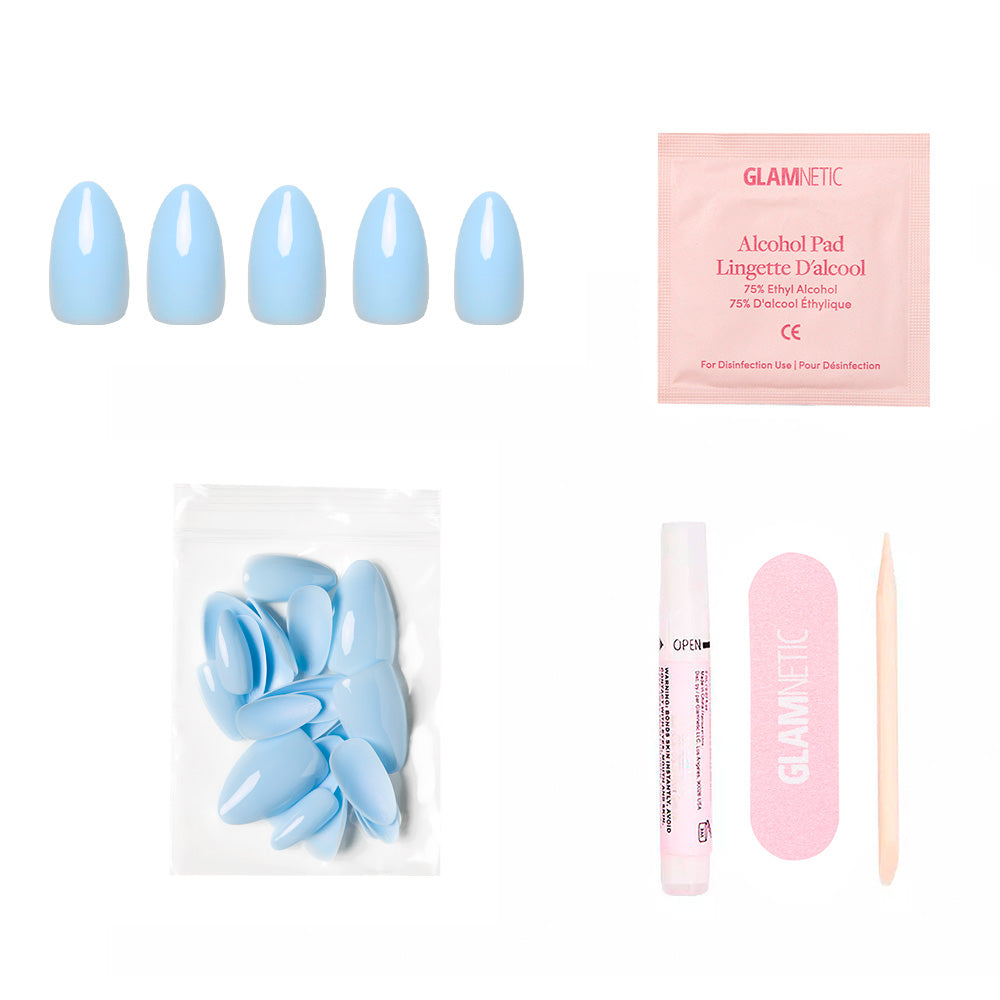 The glamnetic Soft Blue set includes glossy short almond press-on nails, a pink alcohol pad, extra nails in a clear bag, nail glue, a pink nail file, and a wooden cuticle stick—all displayed on a white background. - Product image