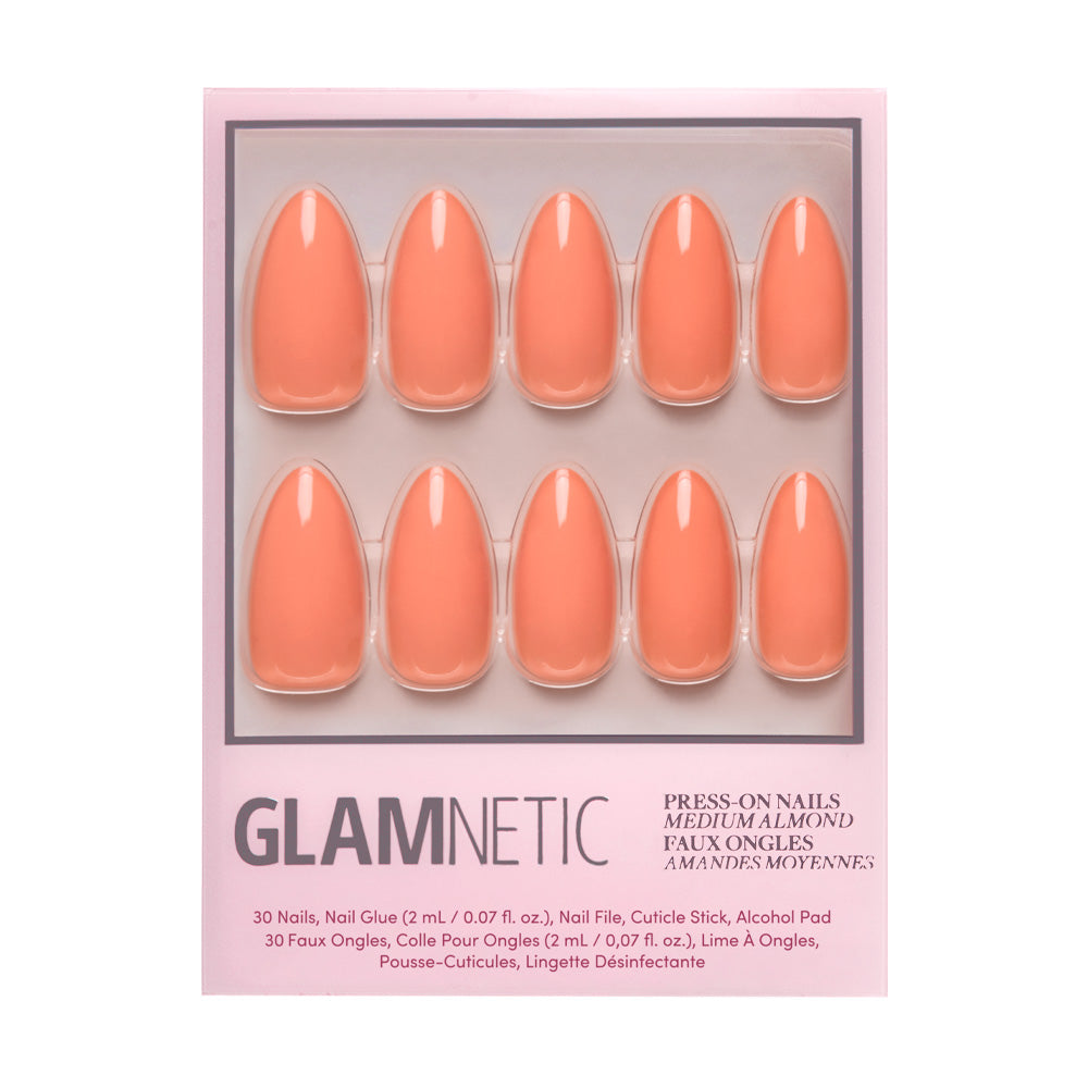 A package of glamnetic Soft Tangerine press-on nails, featuring 10 pastel orange acrylics, is displayed in a clear plastic tray on a pink background. - Product image