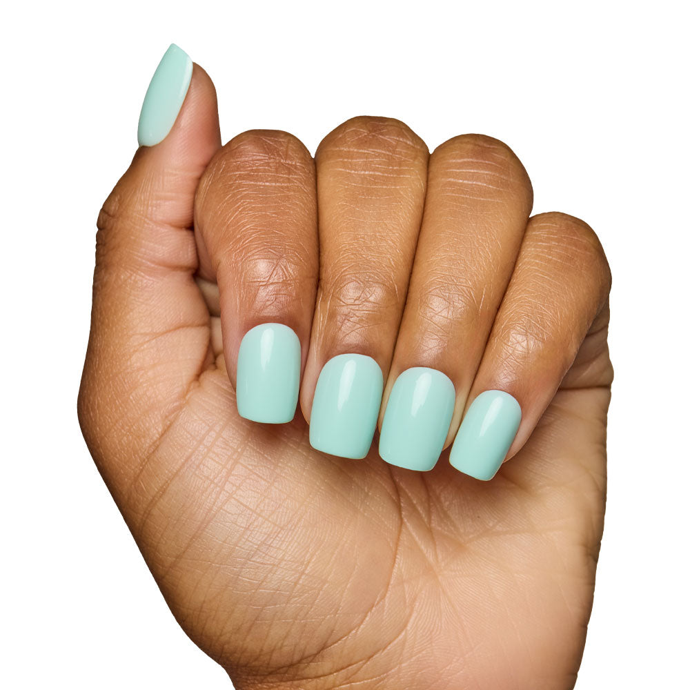 A hand with medium brown skin shows short squoval nails painted in glamnetic’s Soft Teal set. The loose fist pose against a white background highlights the glossy, fresh manicure. - Product image