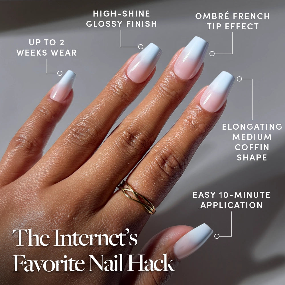 A hand with long, Soft Skyline Nude-to-Blue Ombré French tip nails in a glossy finish is shown. This glamnetic Coffin Nail Set offers up to 2 weeks of wear, features an elongating coffin shape, 10-minute press-on application, and a stunning high-shine ombré French tip effect. - Product image