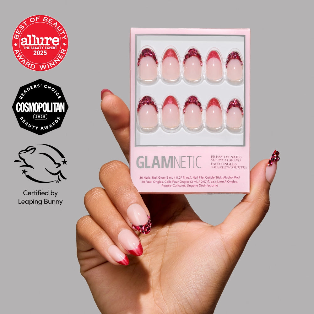A hand with glamnetic Spinel Press-On Nails—pink and red with pink nude French tips—holds the box. Beauty award logos from Allure, Cosmopolitan, and Leaping Bunny certification on the left highlight salon-quality wear.