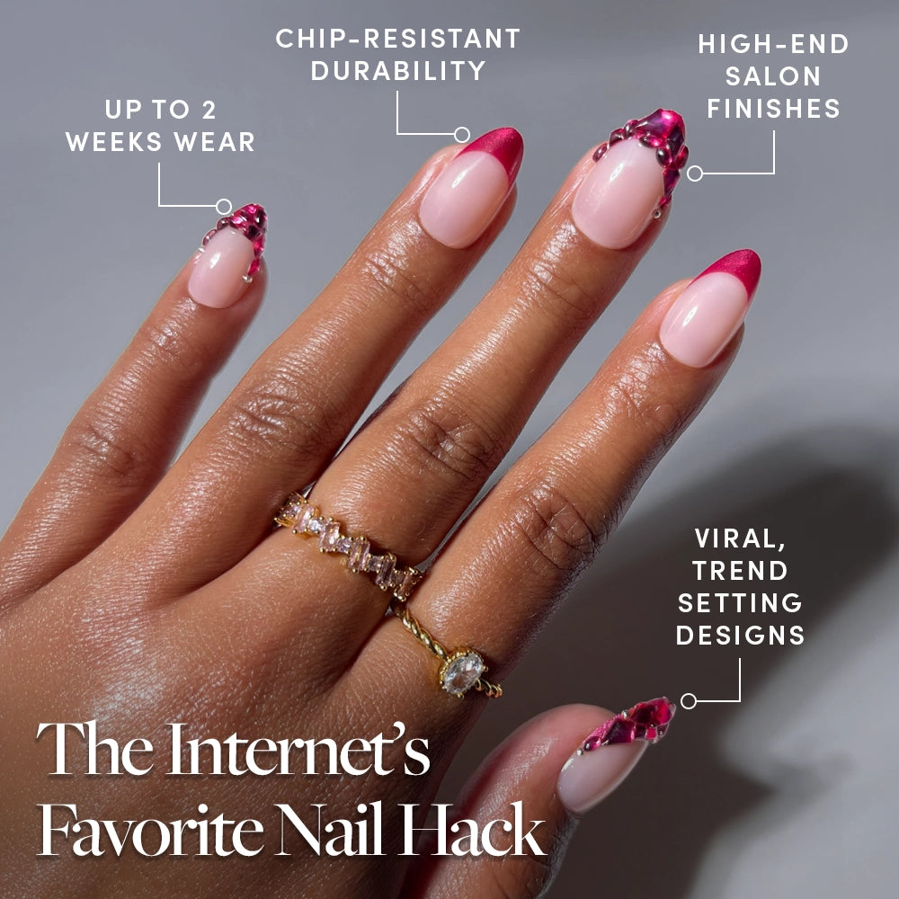 A hand wears glossy pink and red French tip glamnetic Spinel press-on nails adorned with gems, paired with two gold rings. Text highlights: 2 weeks wear, chip-resistant, salon-quality manicure, trendy designs. Title: The Internet’s Favorite Nail Hack—glamnetic Spinel Press-On Nails. - Product image