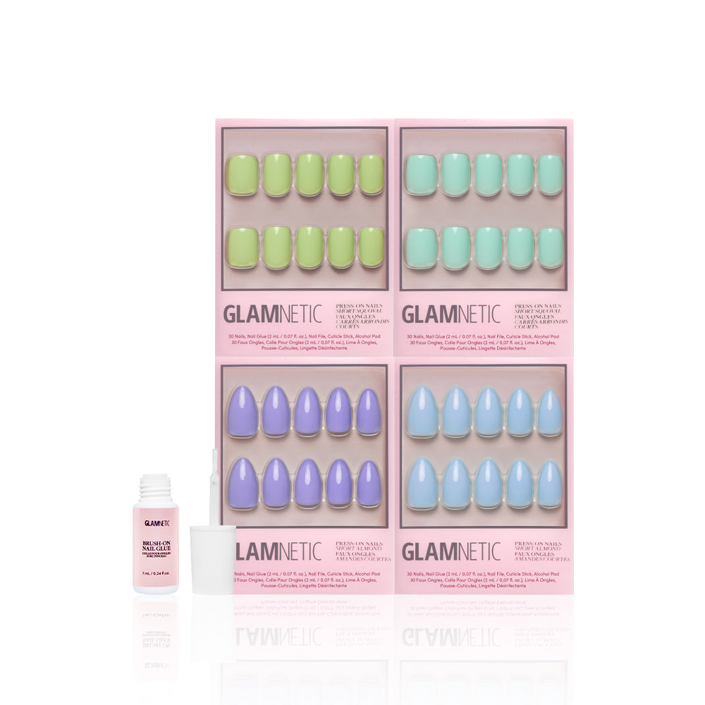 The Spring Day Bundle by glamnetic includes four press-on nail sets in pastel green, mint, lavender, and light blue shades, presented in pink packaging with a bottle of nail glue placed in front. - Product image
