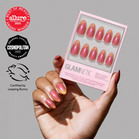 A hand with shimmering pink and gold velvet finish short almond nails holds the Glamnetic Starbeam nail set. Beauty award logos from Allure, Cosmopolitan, and Leaping Bunny cruelty-free certification appear on the left.