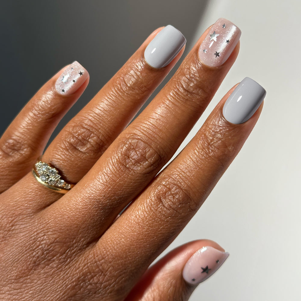 Short, squoval velvet finish Starry Lights nails featuring alternating solid gray polish and sheer, glittery polish with small star accents.