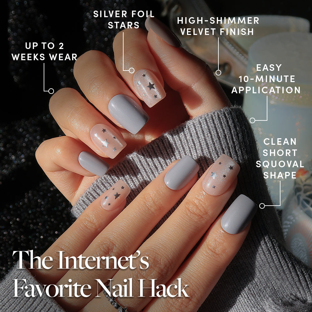 Starry Lights - A hand wearing Starry Lights press-on nails in a short squoval shape, featuring solid grey and sheer glitter with silver star accents, labeled for two-week wear, a shimmer finish, and ten-minute application.