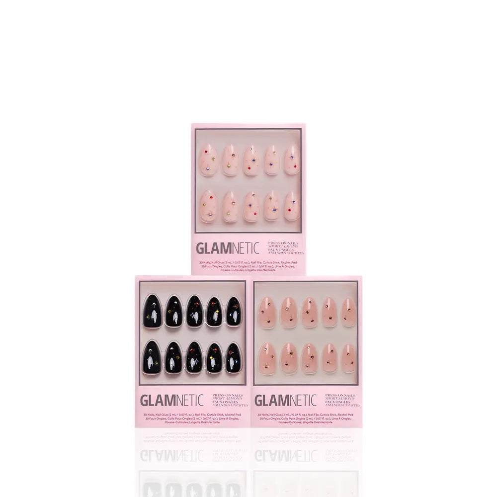 Three boxes of glamnetic Starry Skies press-on nails form a triangle. Two show short almond light pink nails with tiny red hearts; the third displays glossy black nails. All boxes have a pink border and the glamnetic logo at the bottom. - Product image