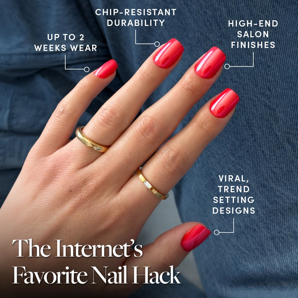 A close-up of a hand with glossy, short squoval Statement Red press-on nails by glamnetic, wearing two gold rings. Text: up to 2 weeks wear, chip-resistant durability, high-end salon finish, viral trend designs. Denim jeans background. - Product image