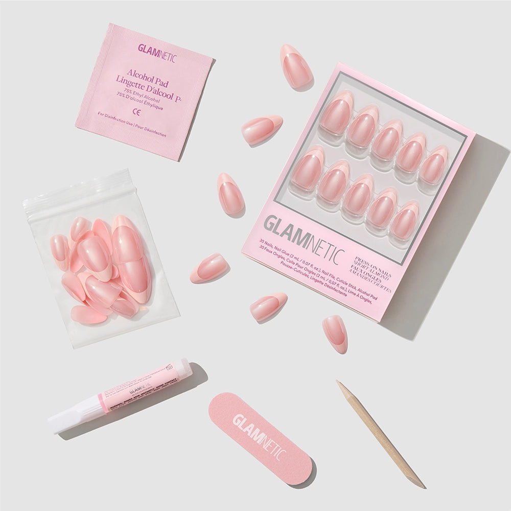 A flat lay of the glamnetic Strawberry Icing Press-On Nail Set displays chic, short almond press-on nails with a glazed French tip design. The set includes nails, nail glue, an alcohol pad, a nail file, a cuticle stick, and extra nails—all neatly arranged on a light gray background. - Product image