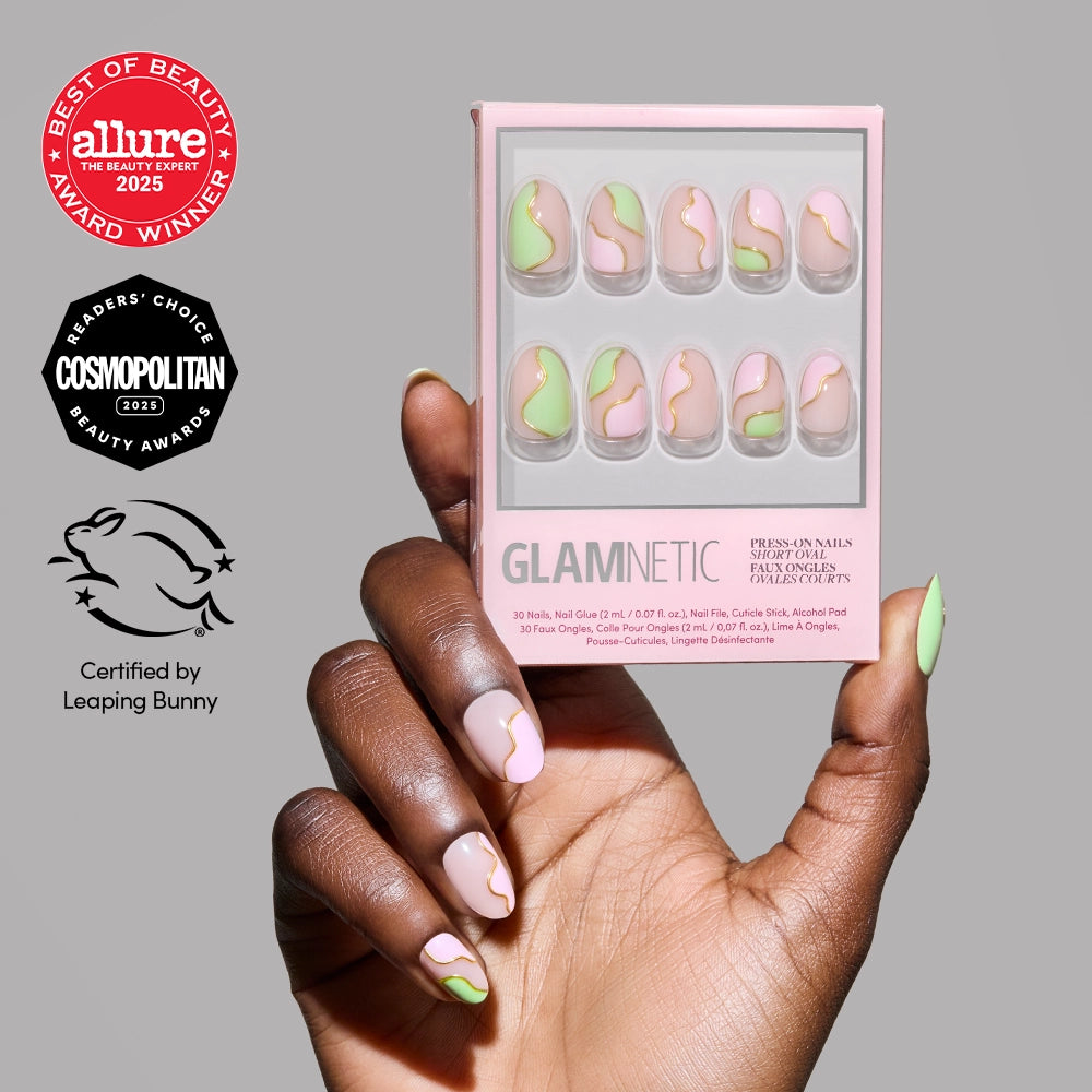 A manicured hand with café-cute nails—pink base, green and gold wavy accents—holds a box of glamnetic Strawberry Matcha Press-On Nails. Beauty award logos and a cruelty-free badge are displayed next to the product.