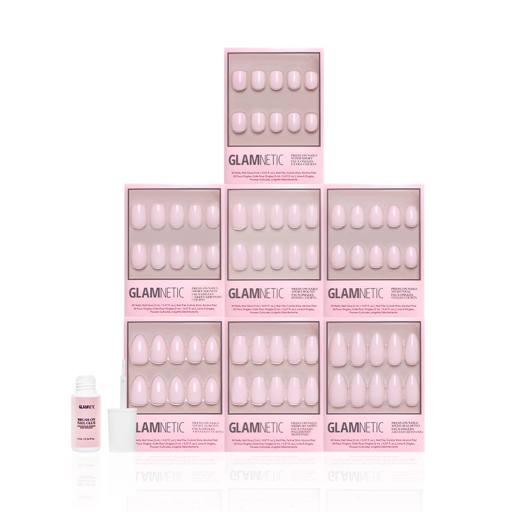 Nine boxes of glamnetic's Strawberry Milk Bundle press-on nails are stacked in a pyramid, with a small nail glue bottle and its cap placed in front, all set against a white background. - Product image