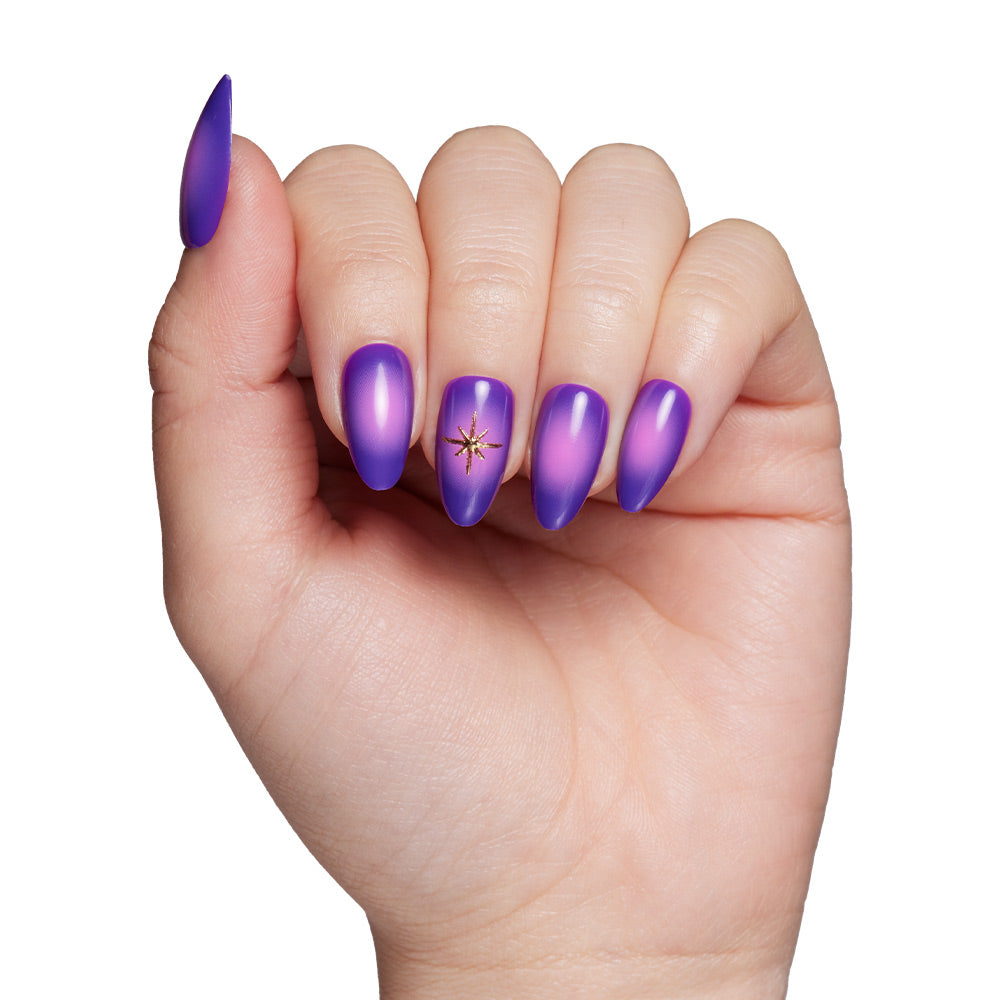 A hand with short almond-shaped nails in glamnetics Tarot mystical purple gradient, featuring a gold star accent on the middle fingernail, posed against a white background. - Product image