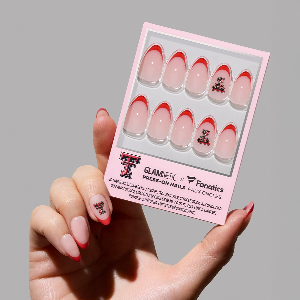 A hand displays the glamnetic Texas Tech Red Raiders Press-On Nail Set, featuring red French tips and the team’s Double T logo, with matching nail art for a bold game-day look. - Product image