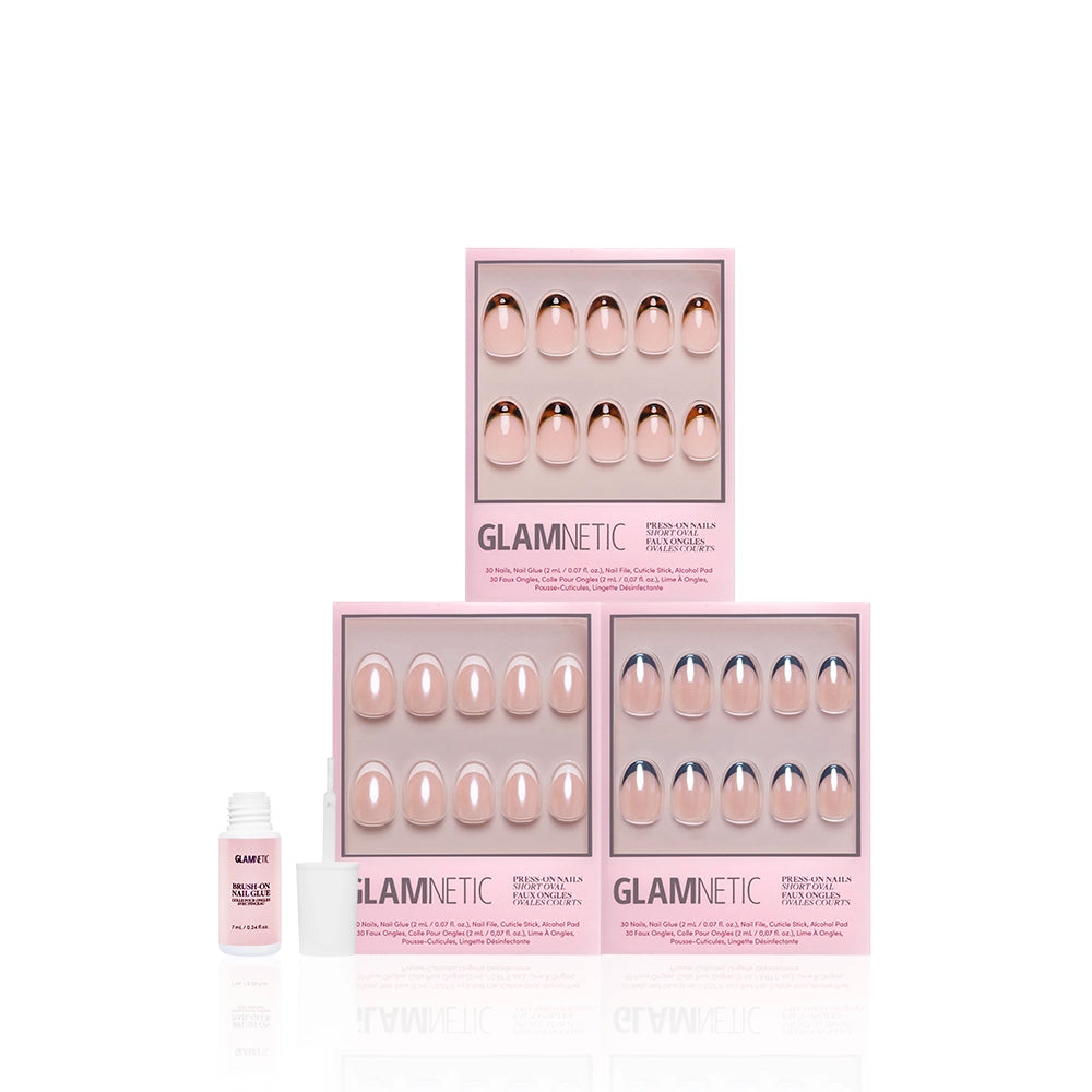 Three boxes of glamnetic’s The Short Oval Frenchies press-on nails—featuring classic nude and pink French tips—are stacked on a white background. A small bottle of nail glue with its cap off sits to the left. - Product image