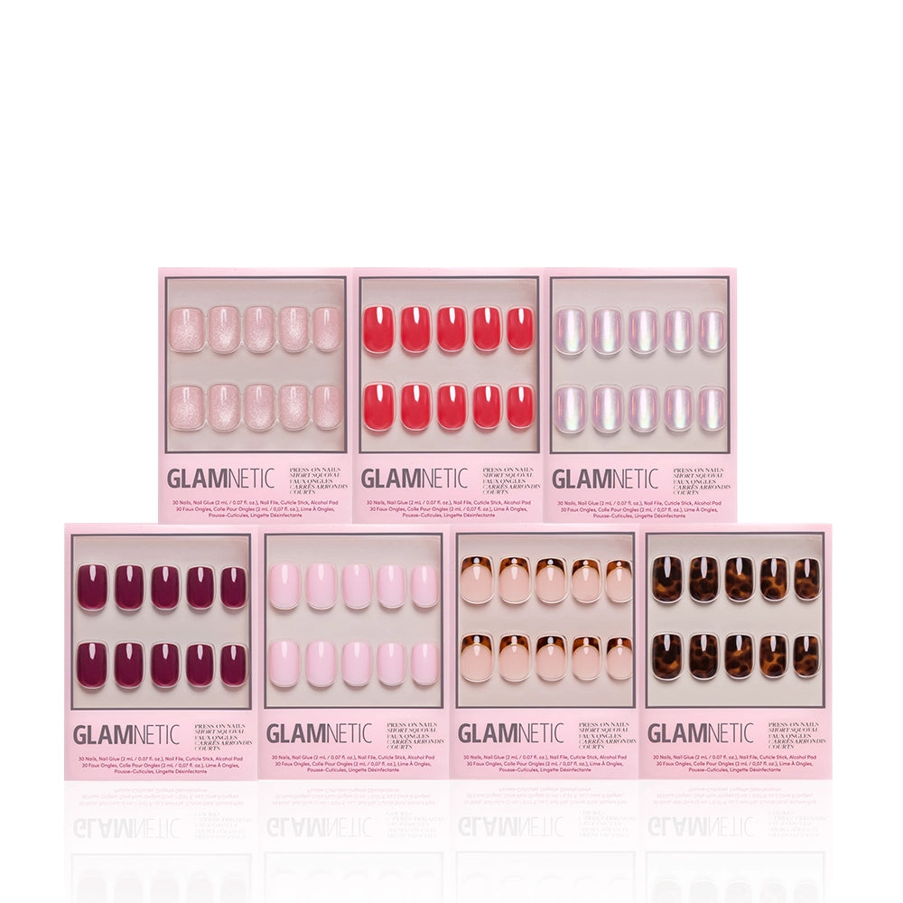 Seven boxes of glamnetic’s The Short Squoval Edit press-on nails—featuring pink, red, white, purple, nude, and tortoiseshell shades—are arranged in two rows on a white background. - Product image