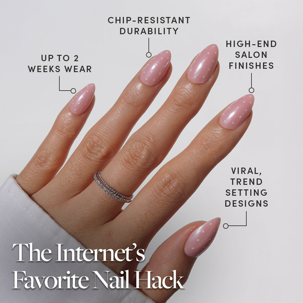 A hand with glossy, almond-shaped "Barely Spotted" press-on nails by glamnetic, featuring pink polish with small white dots. Text highlights chip-resistant durability, up to 2 weeks wear, salon-quality finish, and trendy viral design. - Product image