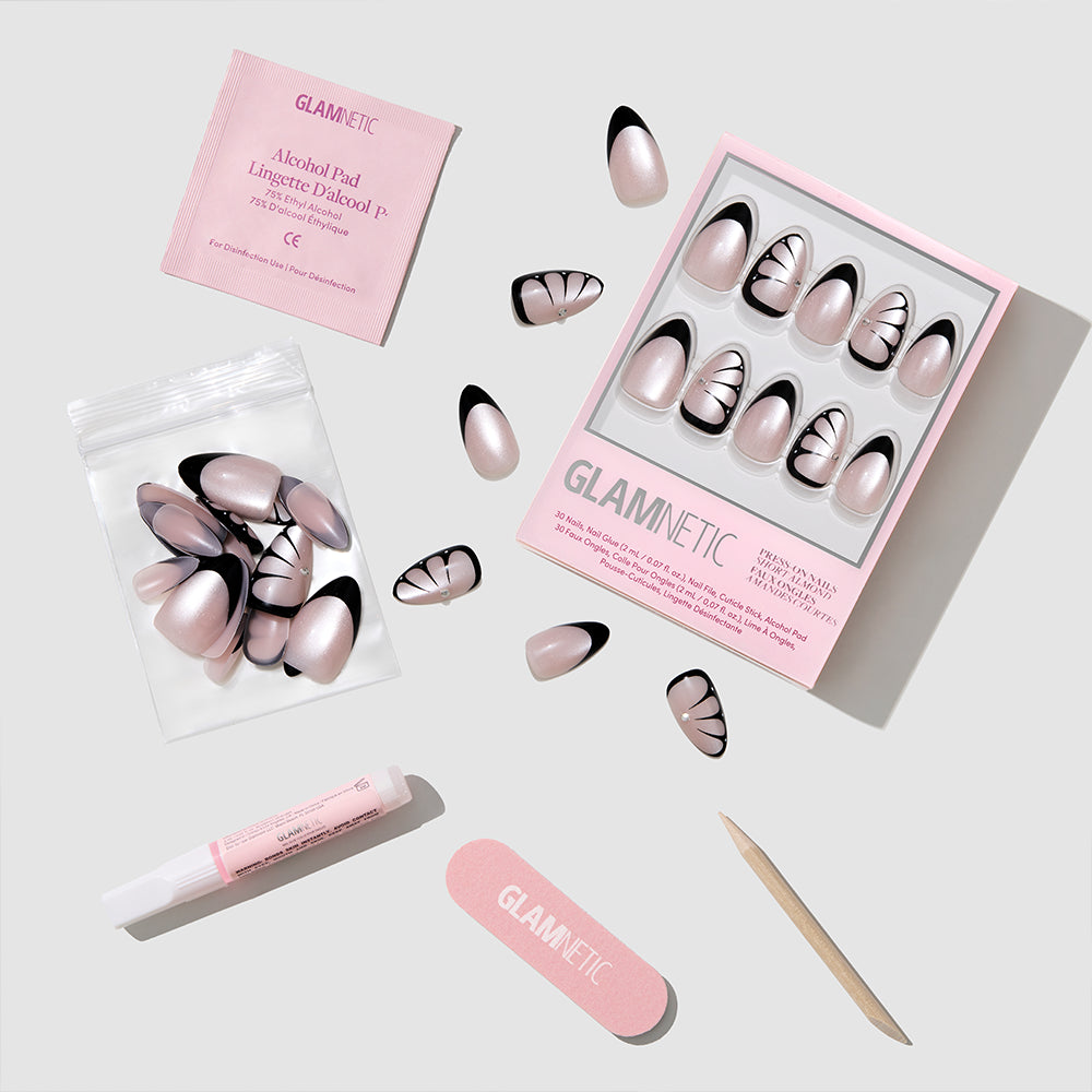 The Butterfly Effect short almond nails by glamnetic feature a pink and black design and are shown with an alcohol pad, nail glue, file, cuticle stick, and extra nails on a light gray background. - Product image