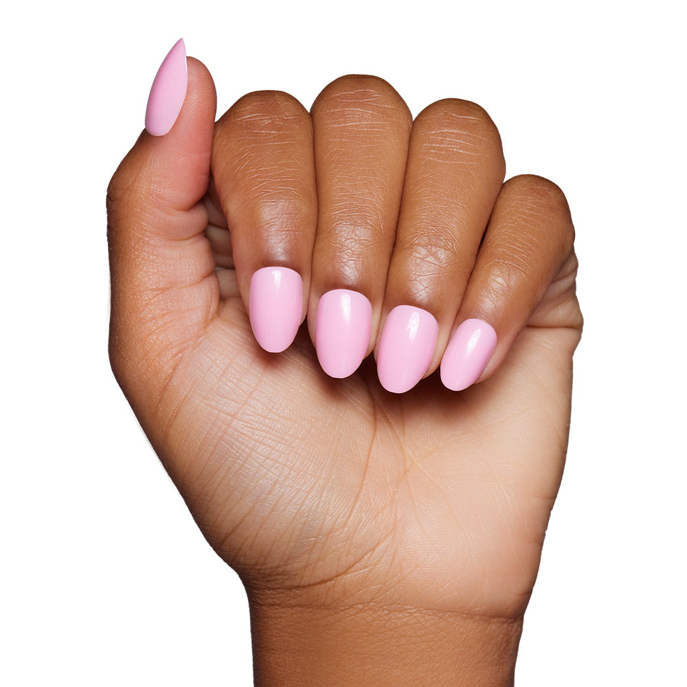 A hand with medium brown skin tone displays glamnetics Think Pink press-on nails, featuring neatly manicured, glossy baby pink polish, against a white background. - Product image