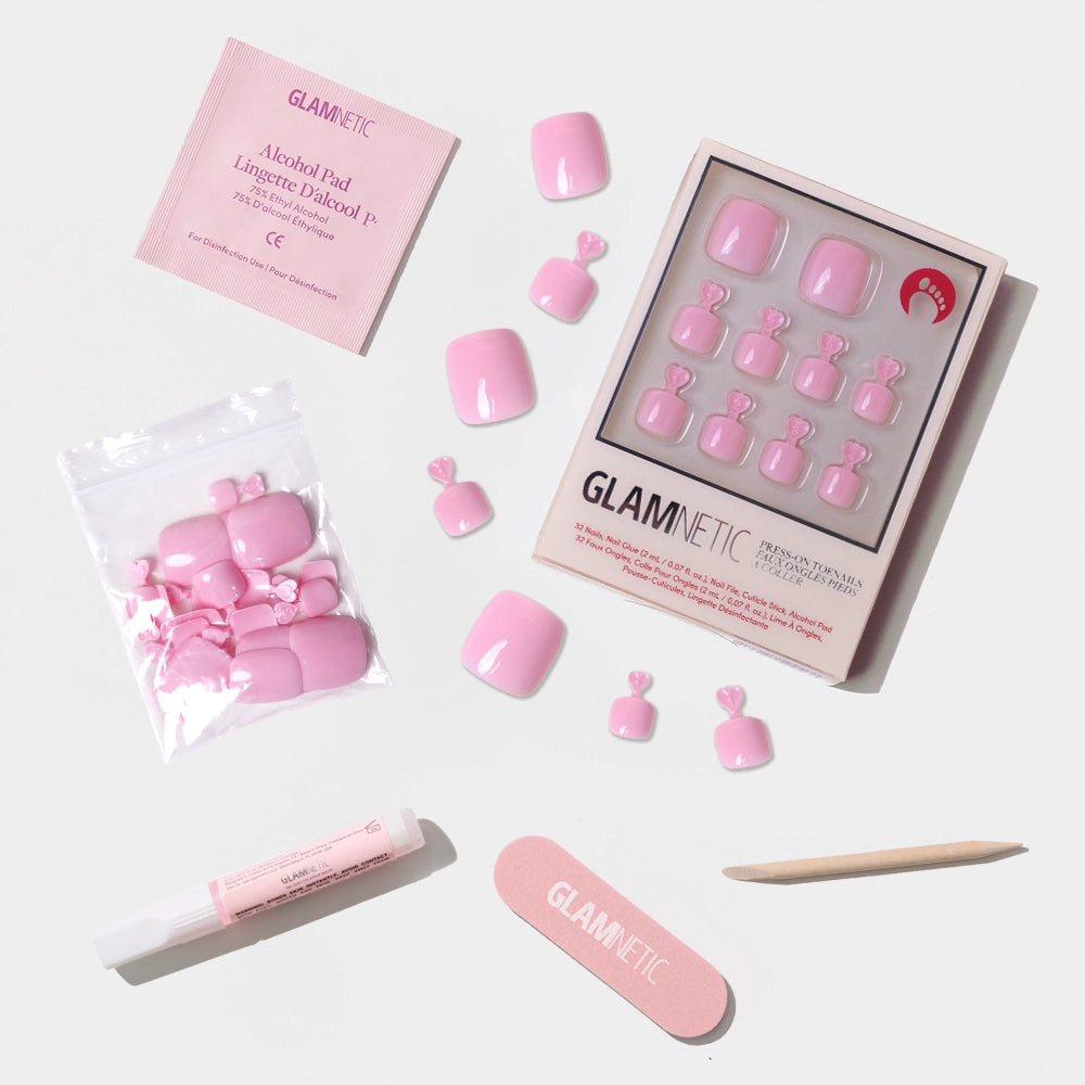 A flat-lay of the Glamnetic pastel pink press-on toenail kit, featuring nails, glue, file, stick, and alcohol pad. - Product image