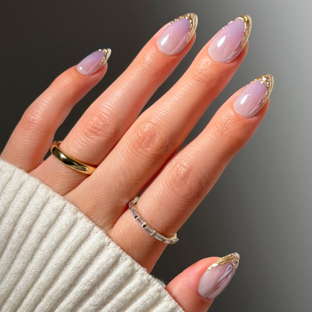 Glamnetic Tipped in Gold short almond press-on nails featuring a sheer light purple base with metallic gold French tips.