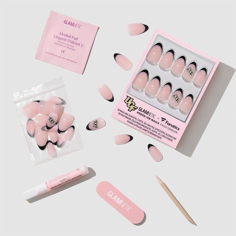 The glamnetic UCF Knights Press-On Nail Set, featuring pink and black French tips, a pink nail file, wooden cuticle stick, nail glue, alcohol pad, and extra nails, is arranged on a light gray background. - Product image