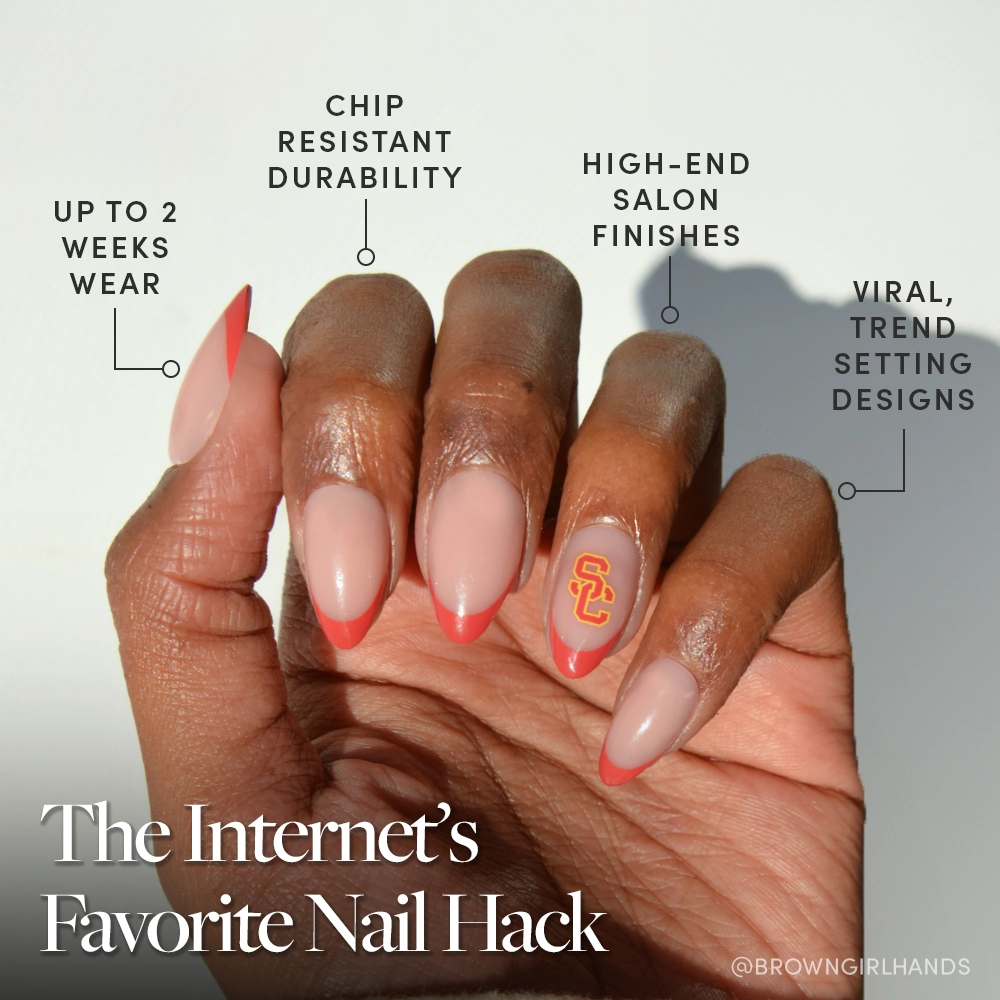 A hand with long, almond-shaped nails features glossy pink polish, coral tips, and a USC logo accent using the glamnetic USC Trojans Press-On Nail Set. Enjoy long wear, chip resistance, salon quality, and trendy designs. - Product image