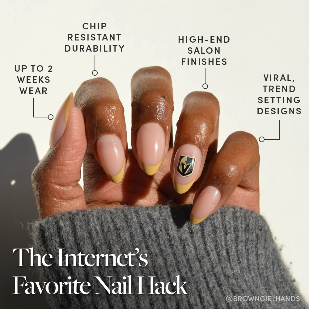 A hand with almond-shaped nails from the glamnetic Vegas Golden Knights Press-On Nail Set features a nude base, yellow tips, and a geometric accent. Enjoy long wear, chip resistance, salon finish, and trendy designs. Sweater sleeve covers the wrist. - Product image