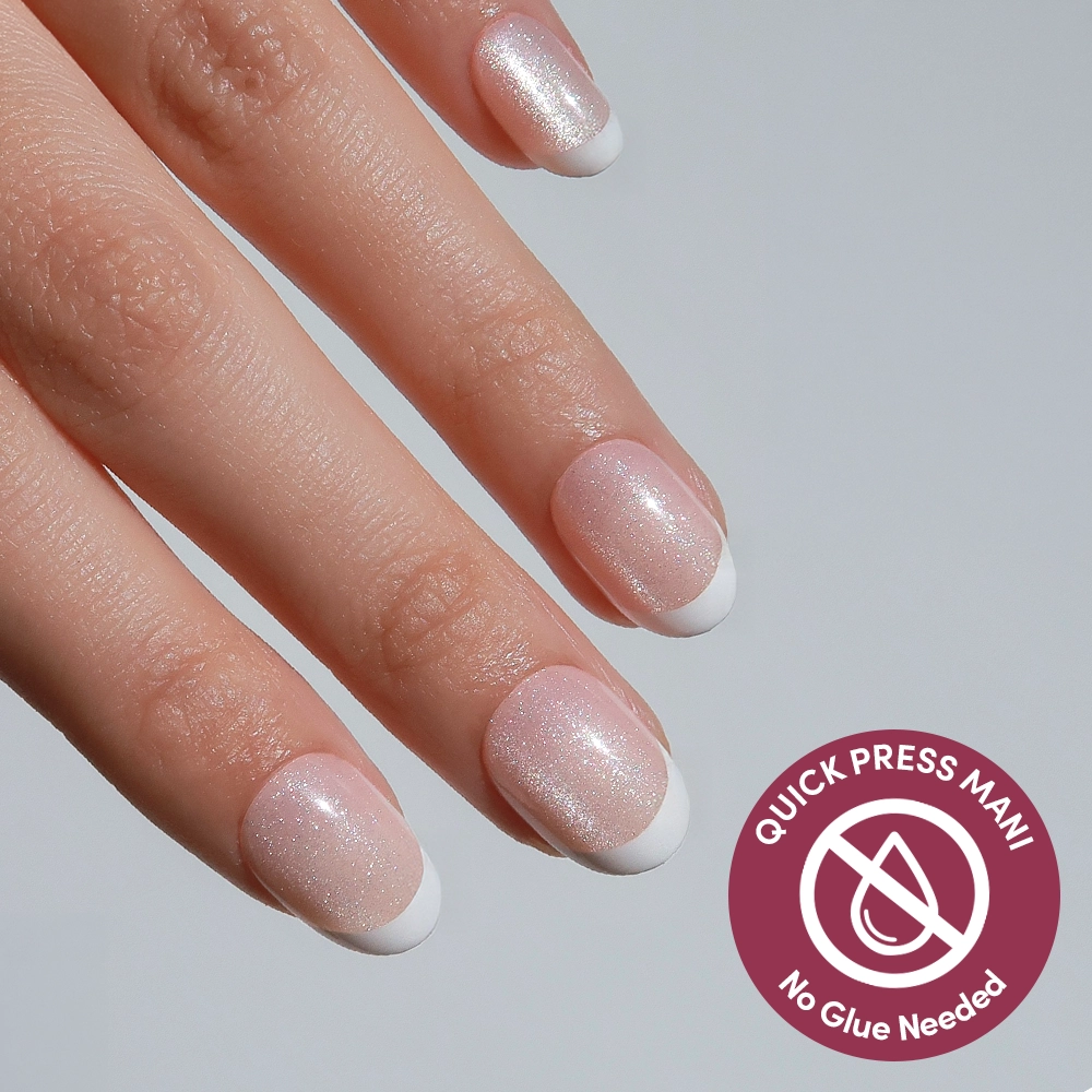 A hand with neatly manicured nails showcases glamnetic’s Velvet French: shimmery light pink base with white French tips. Badge reads, “Quick press mani, built-in adhesive nails, no glue needed.”.