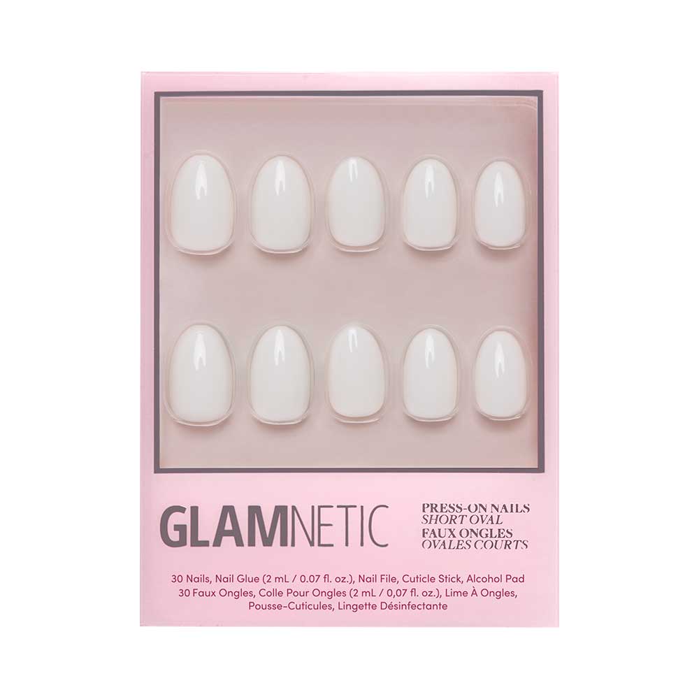 A pink box labeled “glamnetic” holds the White Swan Nail Set—ten short, oval, light pink glossy press-on nails in two rows. English and French text on the box describes the product and its contents. - Product image