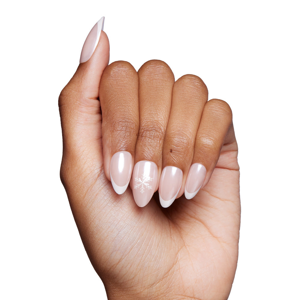 A hand with almond-shaped nails painted light pink with white French tips and snowflake accents on the ring finger, set against a white backdrop—showcasing glamnetic’s Winter Glaze Nail Set for an elegant, wintry style. - Product image