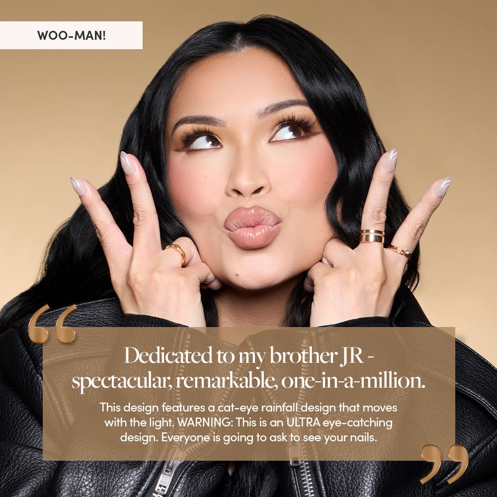 Glamzilla poses playfully against a nude background, flashing peace signs to show off her Woo-Man! swirl nails. Overlaid text dedicates the design to her brother JR and highlights the ultra eye-catching cat-eye rainfall effect. - Product image