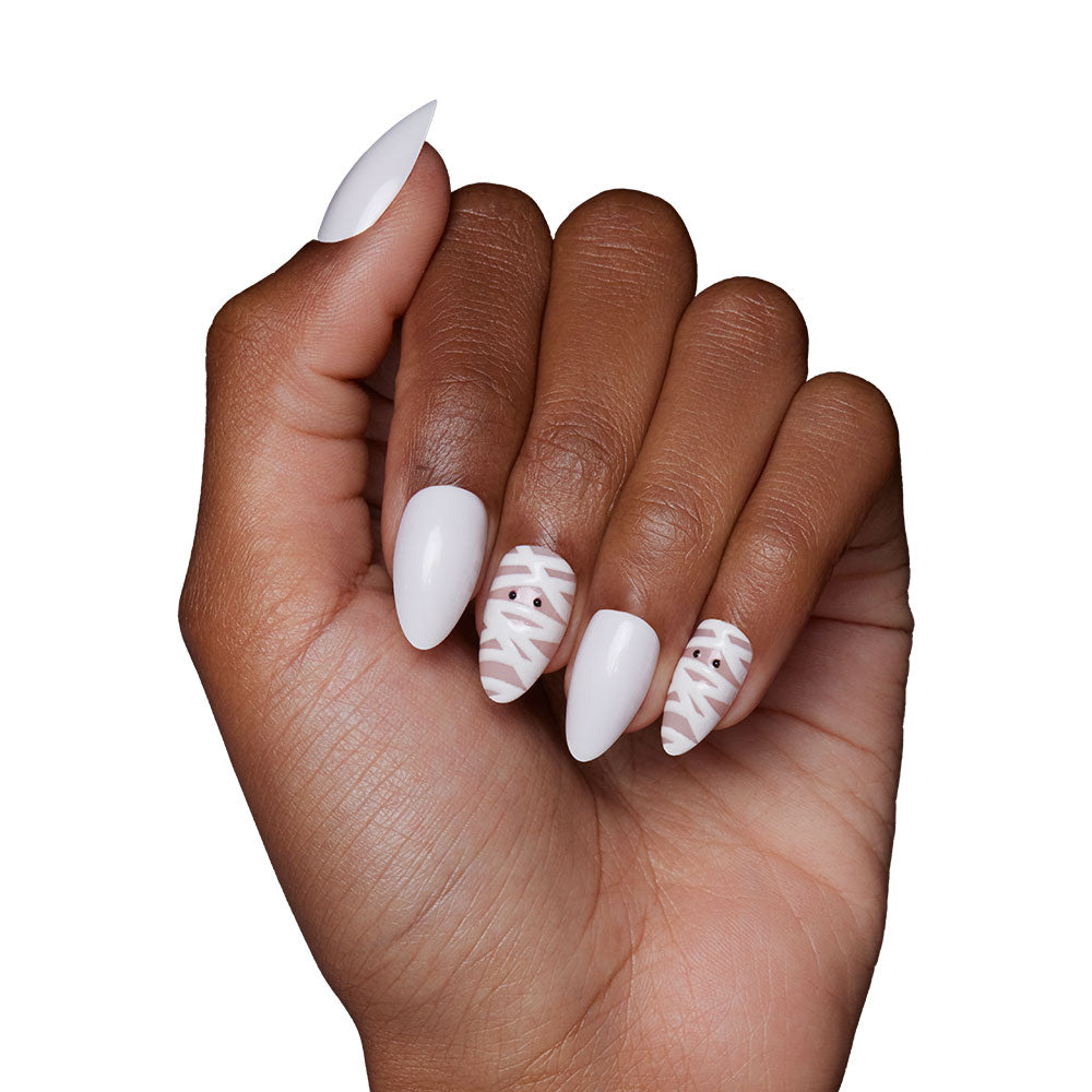 A short almond hand sports glamnetic’s Wrapped Up set: solid white nails with abstract line art on the ring and middle fingers, evoking a playful mummy face, while the others remain a sleek solid white. - Product image