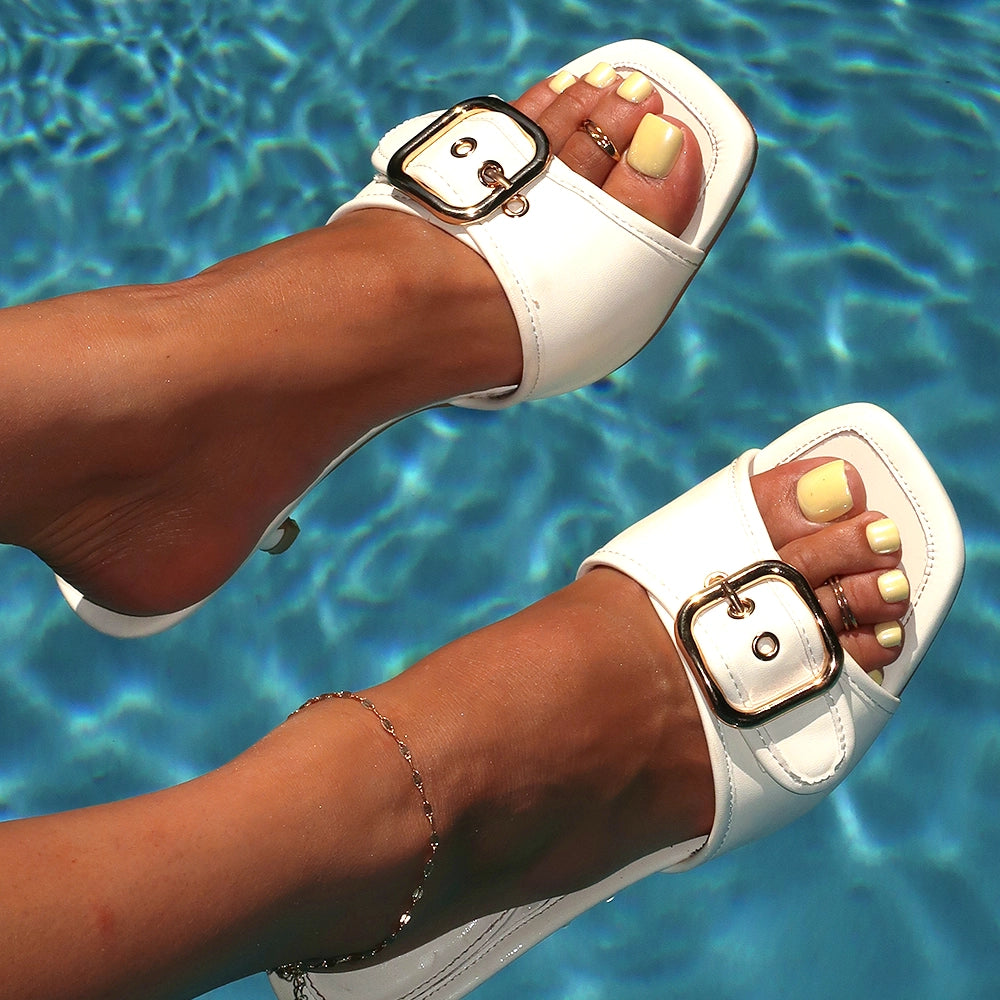 Feet with pastel yellow press-on toenails wearing white sandals, posed above a rippling blue pool, accessorized with an anklet and toe rings. - Product image