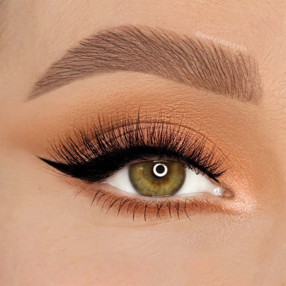 A close-up of a hazel eye with dramatic black winged eyeliner, well-groomed brows, warm blended eyeshadow, and long voluminous glamnetic Gossip lashes crafted from Japanese high-quality synthetic fiber. - Product image